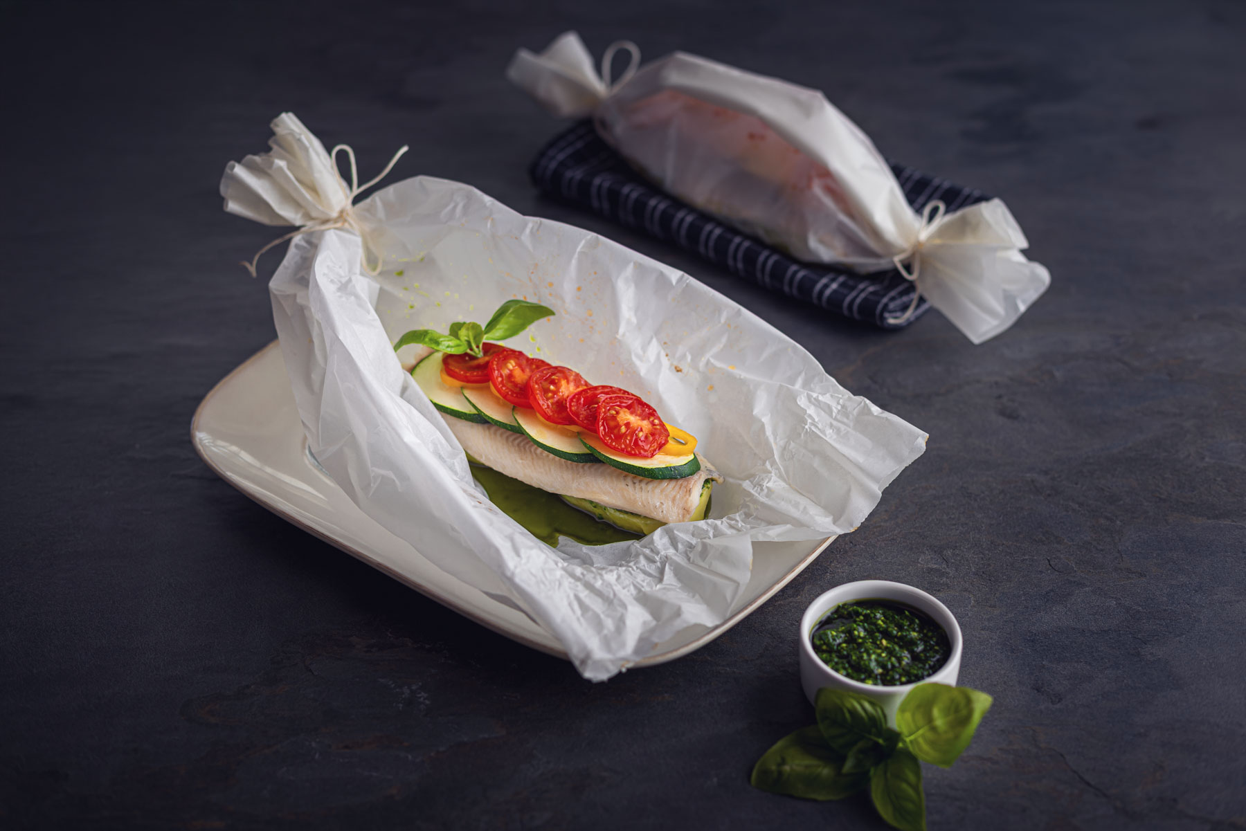 Forellenfilet-Backpapier-Gemuese auf Schieferplatte