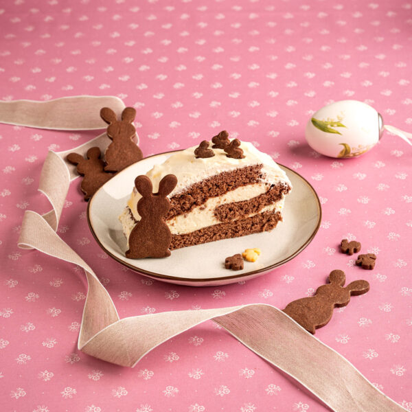 Eierlikörroulade auf weißem Teller vor rosa Hintergrund