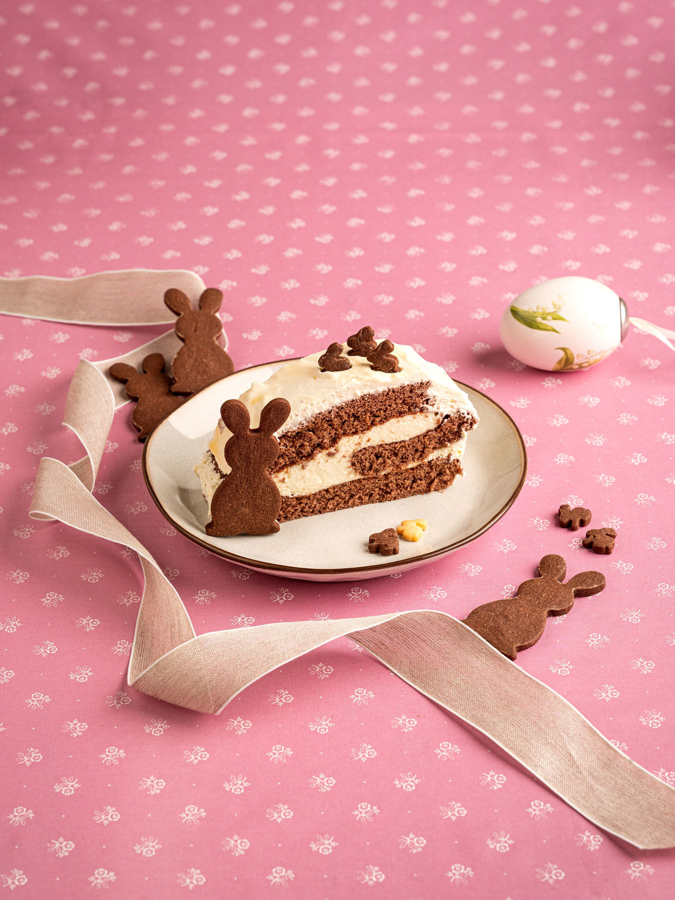 Eierlikörroulade auf weißem Teller vor rosa Hintergrund