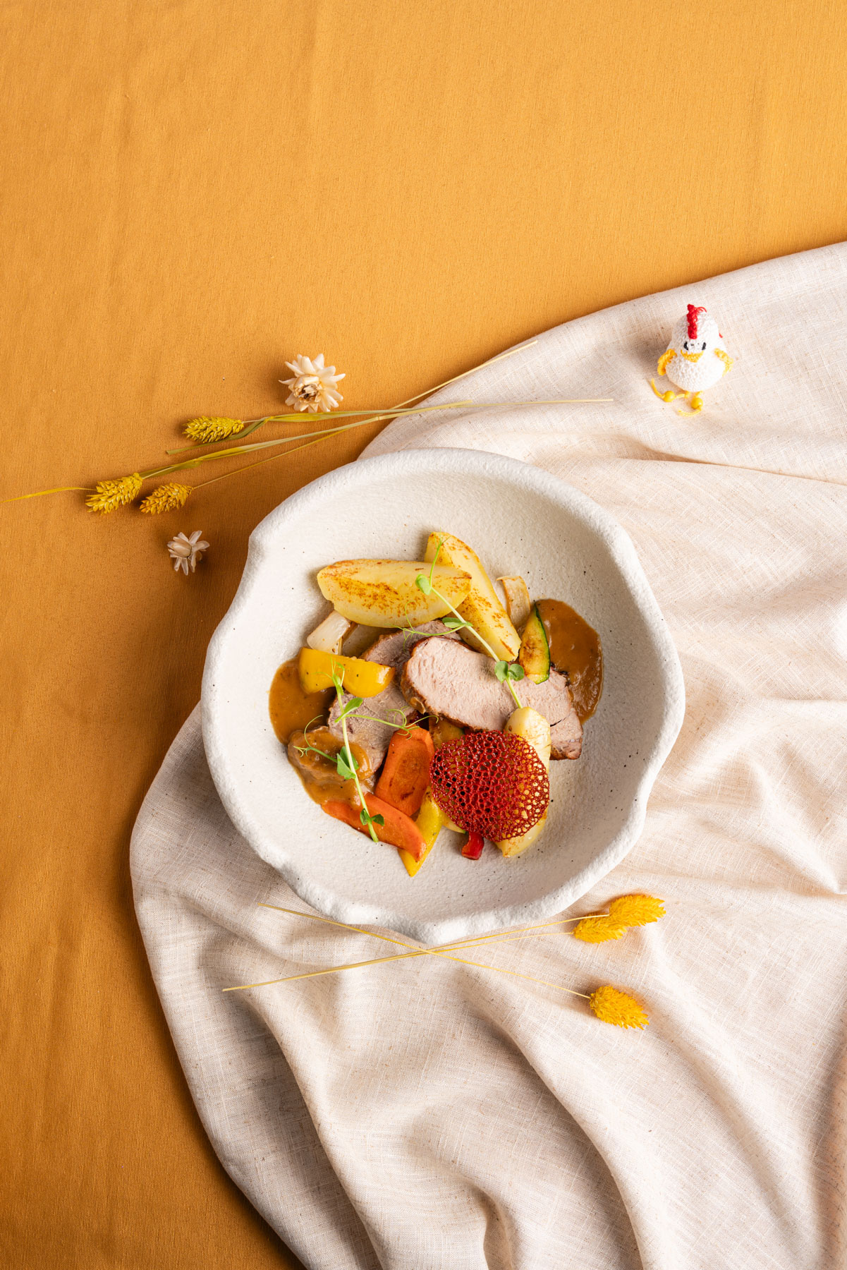 Gebratenes Kalbskarree mit Beilagen in weißer Schüssel auf weißer Tischdecke