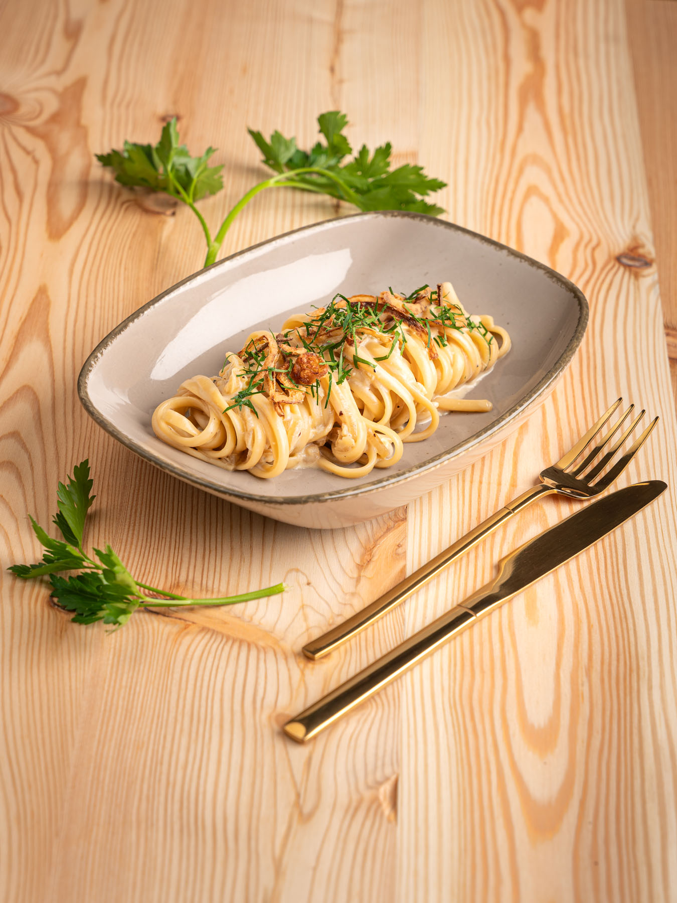 Zwiebelpasta dekoartiv in grauem Teller vor Holzhintergrund